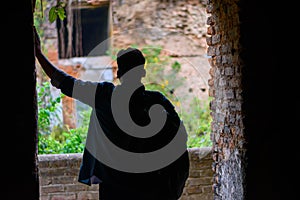 Rear view of mature man posing against door opening in dark room to show outside