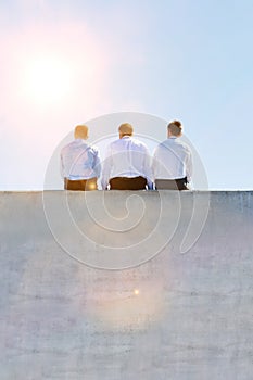 Rear view of mature thoughtful businessmen sitting on office rooftop