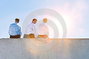 Rear view of mature thoughtful businessmen sitting on office rooftop