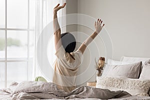 Rear view mature woman awakening in the morning in bedroom