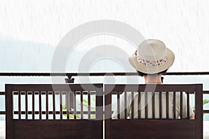 Rear view of middle aged woman on bench in rainy day