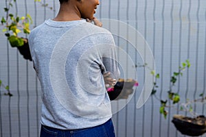 Rear view midsection of african american woman in grey sweatshirt against white fence, copy space