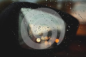 Rear view mirror seen through rain drops on the car window