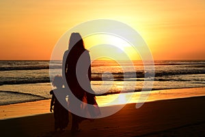 Rear view of a mother and daughter standing on the beach