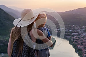 Rear view of mother holding young son on beautiful scenery background. Travel with kids concept