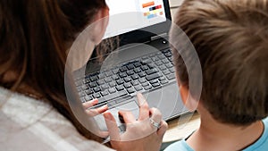 Rear view of mother with little son sitting behind laptop and studying. CHild using computer for education and learning