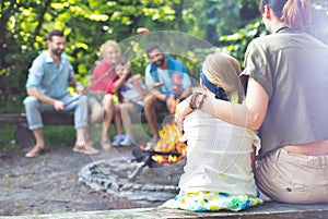 Rear view of mother sitting with arm around daughter while camping at par