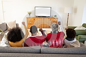 Rear view of Multi generation family cheering while watching sports on TV at home