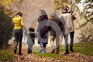 Rear View Of  Multi-Generation Family Having Fun With Children Walking Through Autumn Countryside 