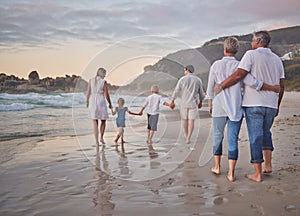 Rear view of Multi generation family holding hands and walking along the beach together. Caucasian family with two