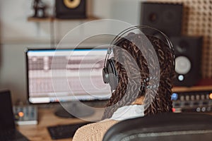 Rear view of musician producer, sound engineer uses control panel to record new album track in soundproof room