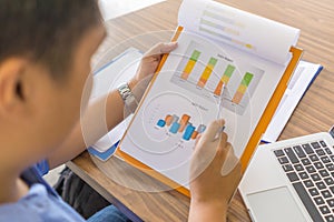 Rear view of office man checking financial graph on report