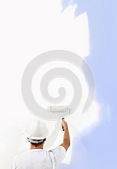 Rear view of painter man with paint roller painting on blank wall, isolated on white, copy space
