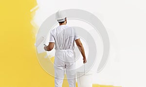 Rear view of painter man painting the wall, with paint roller and bucket, isolated on big empty copy space