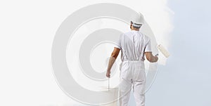 Rear view of painter man painting the wall, with paint roller and bucket, isolated on big empty white copy space