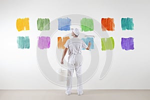 Rear view of painter man who make and chooses from various colors