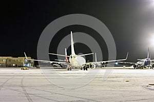 Rear view of the passenger aircrafts on the airport apron at winter night