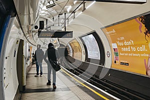 Rear view of people walking on the platform of Embankment tube station, London, UK