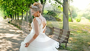 Rear view photo of happy smiling young bride walking away from camera in park