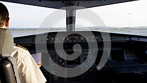 Rear view of pilot operating controls of corporate jet. Captain in the aircraft cockpit, preparing for flight departure