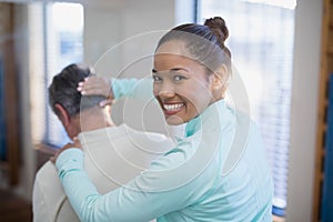 Rear view of portrait of smiling female therapist giving neck massaging to senior male patient