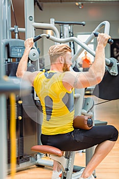 Rear view of a powerful bodybuilder with strong arms exercising at the gym