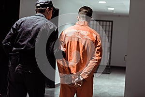 rear view of prison officer leading prisoner in handcuffs photo