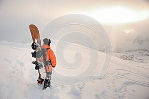 Rear view of professional snowboarder standing on the mountain p