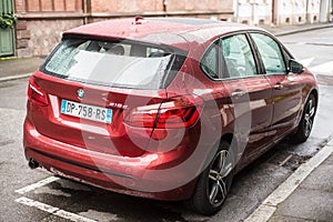 rear view of red bmw 218 parked in the street by rainy day