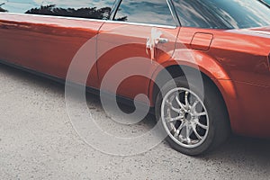 A rear view of a red long limousine with a decoration on the back door handle. The rear part of a festive red limousine