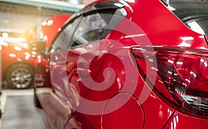 Rear view of red SUV car parked in car repair shop. Red car in workshop of service station. Vehicle inside garage workshop.