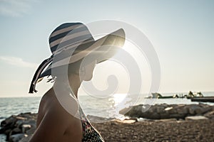 Rear view of a relaxed woman wearing a striped straw hat at the
