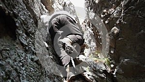 Rear view of rock climbing man, climbing with hands, legs and feet on rock, very difficult movement. Footage. Mountain