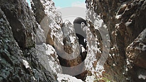 Rear view of rock climbing man, climbing with hands, legs and feet on rock, very difficult movement. Footage. Mountain