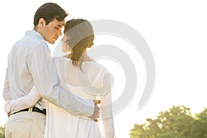 Rear view of romantic couple standing arms around against clear sky