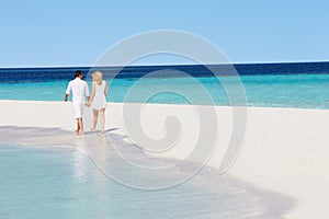 Rear View Of Romantic Couple Walking On Tropical Beach