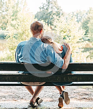 Rear view of romantic senior couple hugging on a park bench