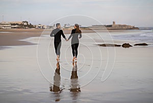 Rear View Of Romantic Young Couple Running On The Beach Together