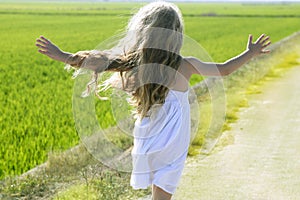 Rear view running open arms little girl in meadow