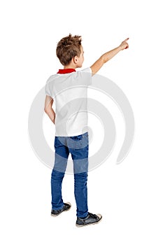 Rear view of a school boy over white background pointing upwards