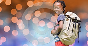 Rear view of school child carrying backpack over bokeh