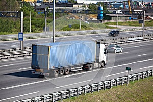 Rear view of semitrailer with blue container driving on highway