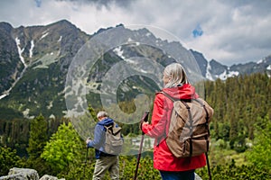 Rear view of senior couple hiking together in autumn mountains.