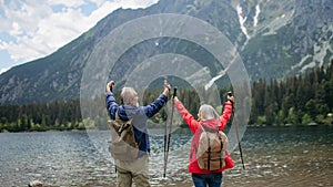 Rear view of senior couple hiking together in autumn mountains.