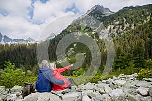 Rear view of senior couple resting during hike in autumn mountains.