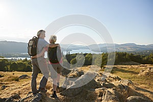 Rear View Of Senior Couple Standing At Top Of Hill On Hike Through Countryside In Lake District UK