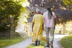 Rear View Of Senior Couple Walking Pet Bulldog In Countryside