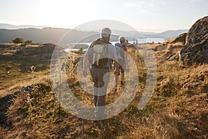 Rear View Of Senior Couple Walking On Top Of Hill On Hike Through Countryside In Lake District UK