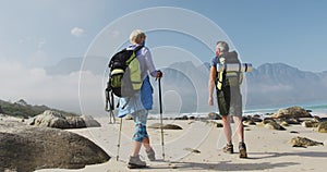 Rear view of senior hiker couple wearing face mask with backpacks and hiking poles