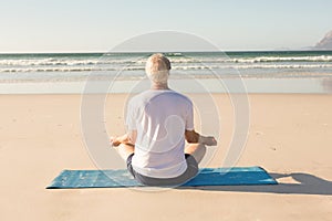 Rear view of senior man meditating at beach